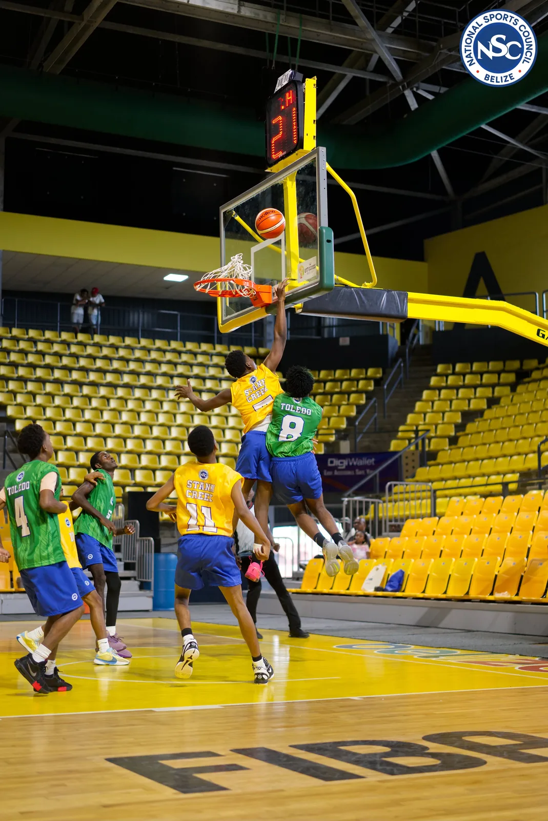 Stann Creek and Toledo players contesting a layup under the basket at the NSC Super Nationals basketball final